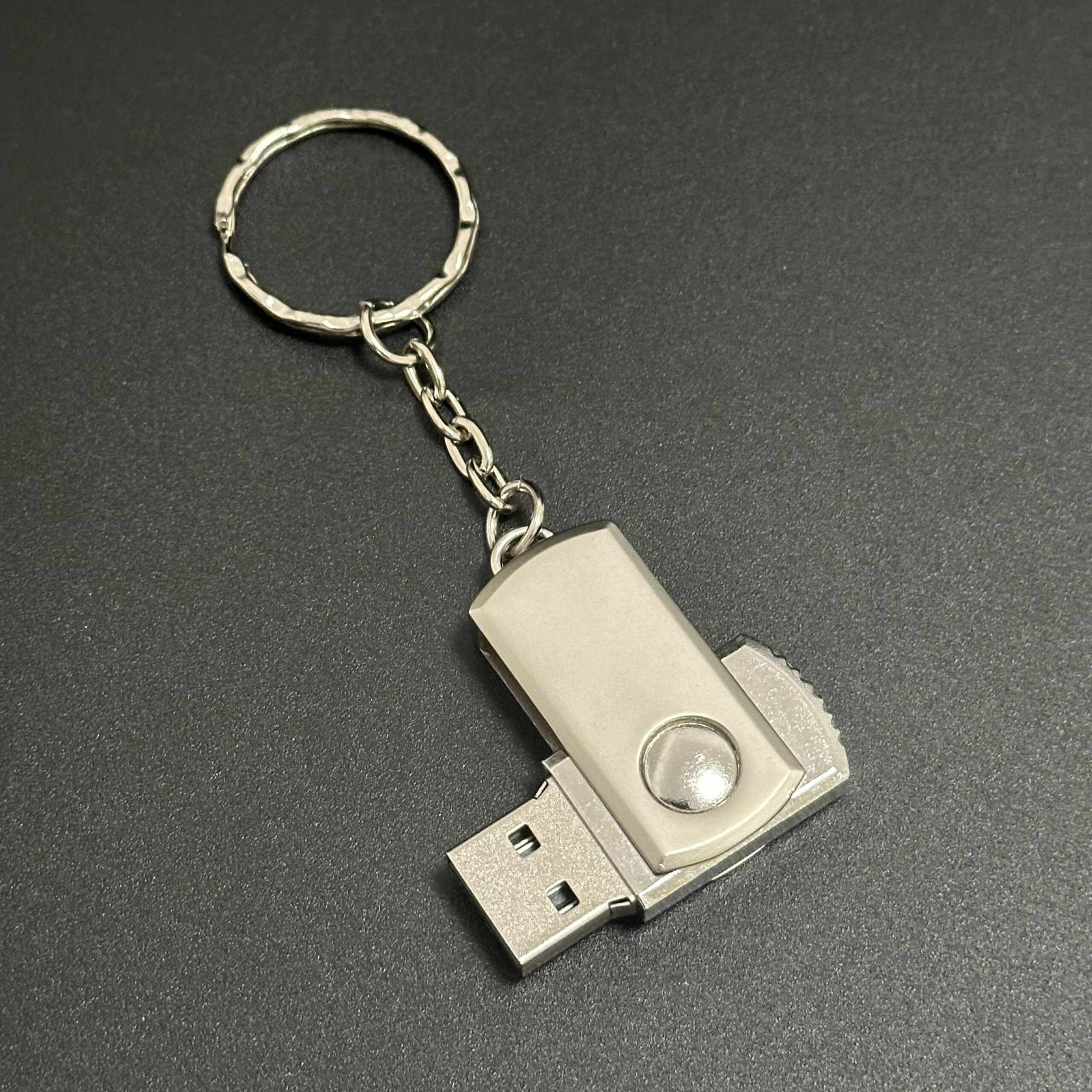 Metal swivel pendrive placed on desk next to laptop for work or study use