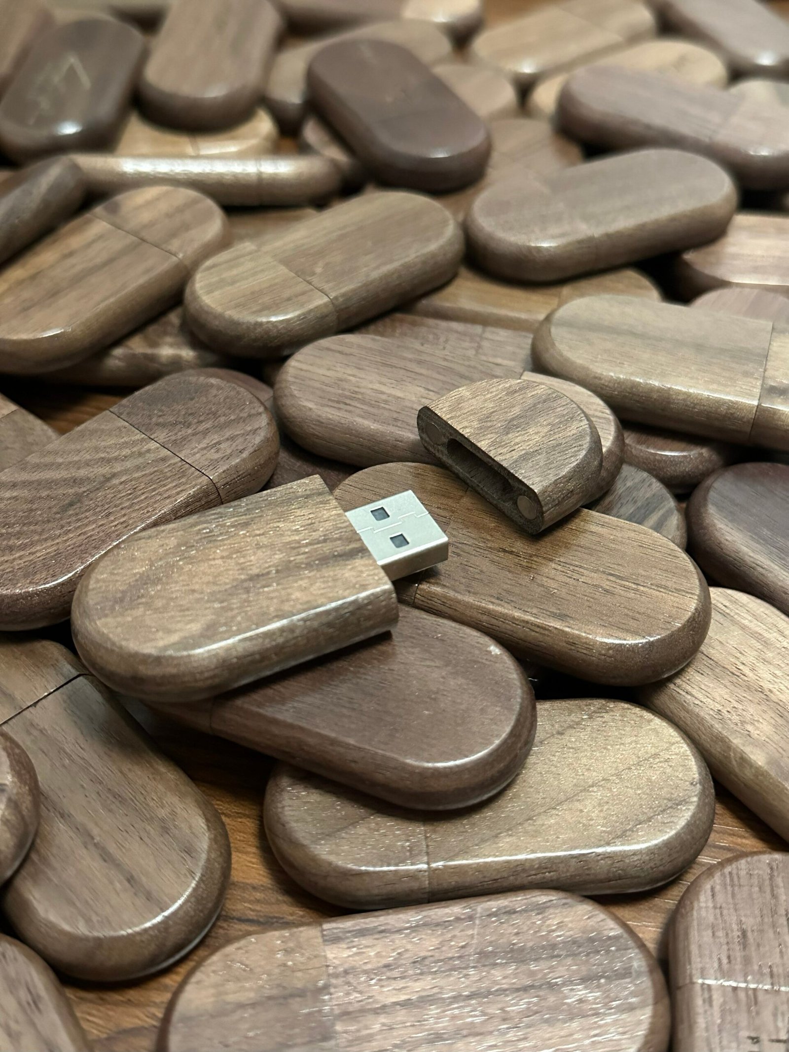 Hand separating the walnut wood cover from the USB body, exposing silver metallic USB plug and built-in magnetic dots