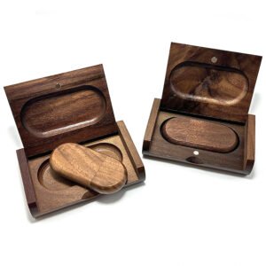 Handcrafted solid walnut wood USB drive with magnetic cap closure, resting on a wooden gift box lid in natural daylight