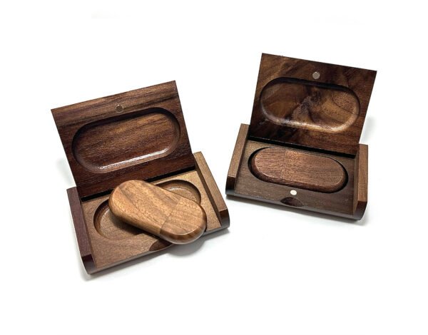Handcrafted solid walnut wood USB drive with magnetic cap closure, resting on a wooden gift box lid in natural daylight